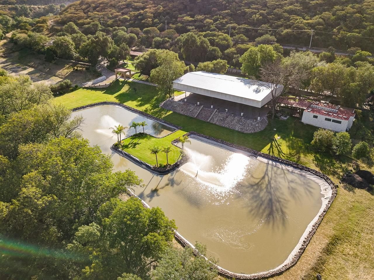 Vista aérea de la hacienda: lago con fuentes, isla de palmeras y el Salón del Lago