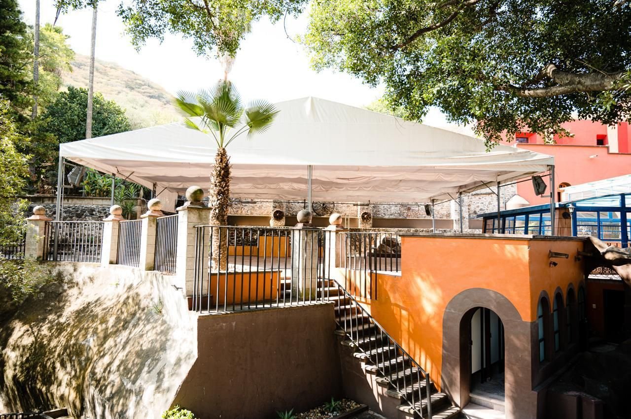 Terraza La Capilla: carpa sobre terraza con barandal de herrería entre árboles