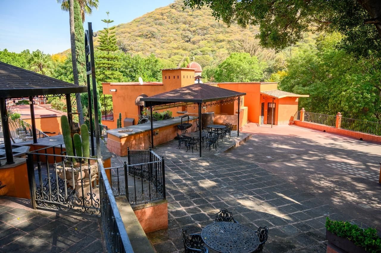 Patio con pérgolas, mesas de herrería y vista al cerro